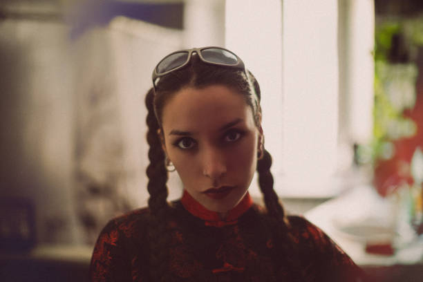 A young woman with braided hair, dark lipstick, and sunglasses on her head, embodying '90s fashion style.